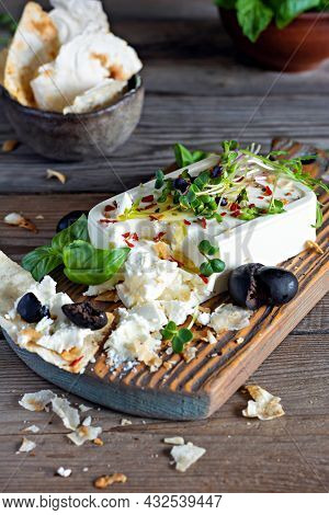 A Piece Of Fresh Feta Cheese (paneer) With Olives, Herbs, Spices And Slices Of Flatbread (tortilla, 