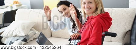 Woman In Wheelchair With Laptop On Her Legs And Her Friend Waving Her Hand In Gratitude