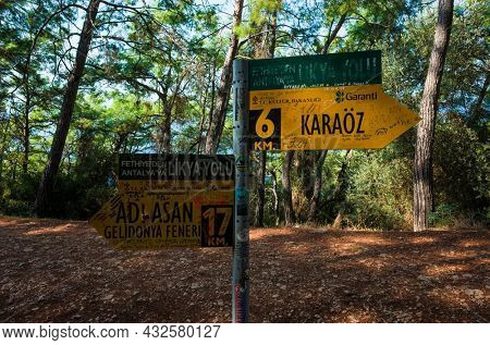 Lycian Way, Turkey - 28 October, 2019: Lycian Way direction yellow signpost pointing to Kakaoz and Adrasan with Gelidonya lighthouse, Mediterranean coastal trail