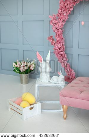 Two Ceramic Statuette Easter Bunnies Stand On A White Wooden Table. Easter Interior Home. Easter Hun