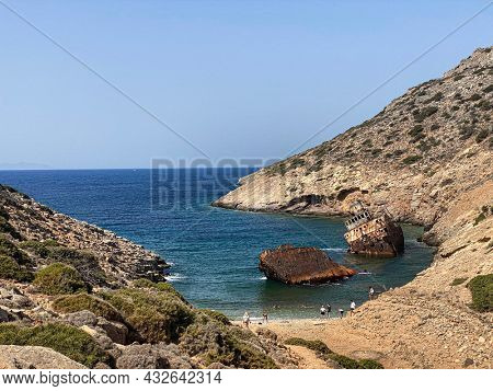 People on the beach visiting Shipwreck Olympia boat in Amorgos island during summer holidays, at the coastal rocky area, , Cyclades, Greece. Travel background