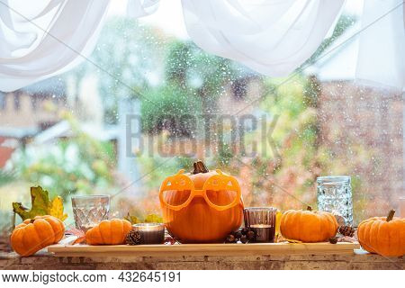 Halloween Autumn Cozy Mood Composition On The Windowsill. Pumpkins In Funny Sunglasses, Candles, Dri