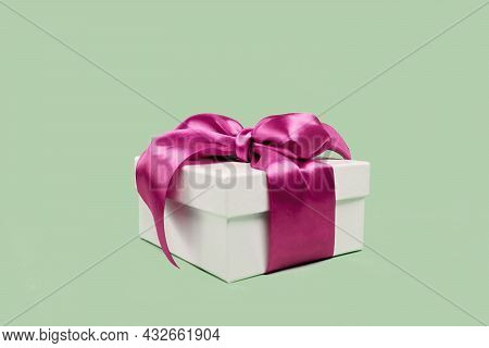 White Gift Box With Pink Ribbon On Soft Green Background