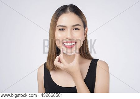 Young Smiling Woman Holding Invisalign Braces In Studio, Dental Healthcare And Orthodontic Concept