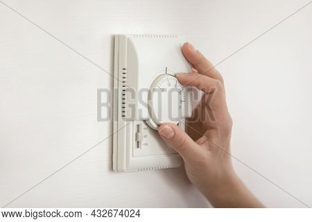 Young Woman Hand Switch On Temperature Regulator On Wall Panel