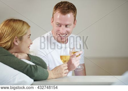 Joyful Young Boyfriend And Girlfriend Clinking Champagne Glasses When Spending Evenig At Home