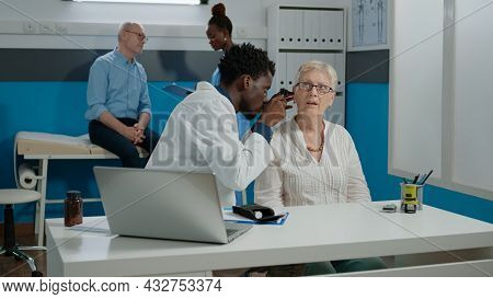 Otologist Doing Ear Consultation For Elder Patient Using Professional Otoscope At Healthcare Facilit