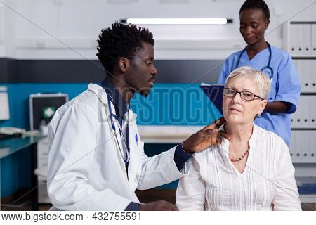 African American Medical Staff Consulting Senior Woman In Healthcare Cabinet At Clinic. Black Doctor