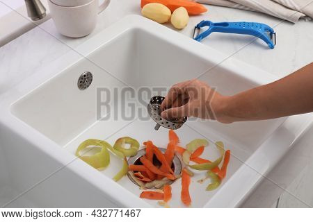 Woman Putting Vegetable Scraps In Garbage Disposal At Home, Closeup