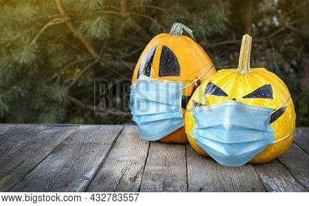 Celebrating Hallowin During A Pandemic Concept With Halloween Pumpkins In Medical Masks.