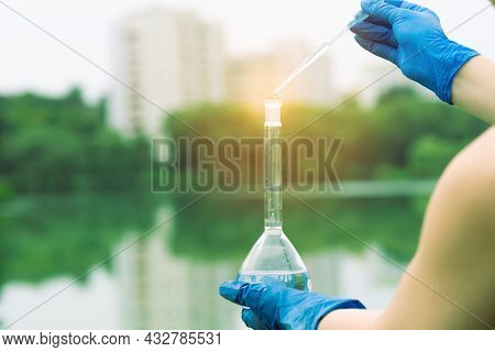 Sampling From Open Water. A Scientist Or Biologist Takes A Sample Of Water From A City Reservoir. A 