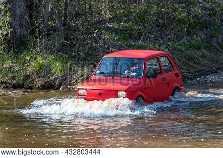 Madona, Latvia - May 01, 2021: Red Oldtimer Car Fiat 126 Overcomes Water Obstacle
