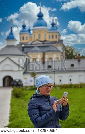 A Believing Parishioner With A Telephone Against The Background Of The Orthodox Church. Woman With S