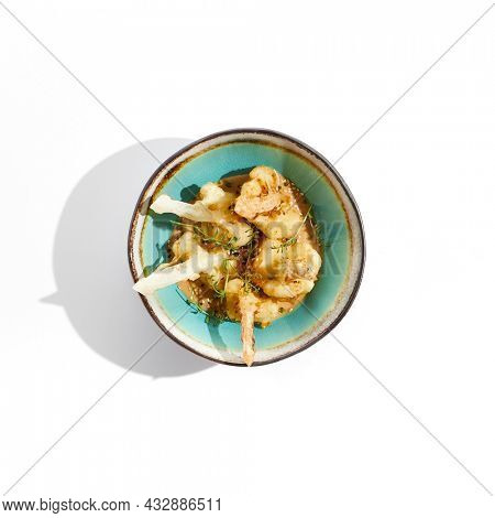 Fried tempura cauliflower with peanut sauce in bowl. Vegeterian hot dish - florets cabbages roasted  in batter on white background. Veggie menu for asian restaurant. Hot vegan appetizers plant based