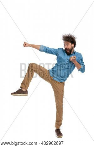 fighter standing on one leg and giving a round kick and a jab on white background