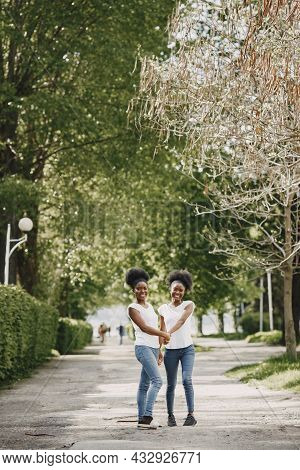 Twin Sisters Holding Hands And Walking In A Park