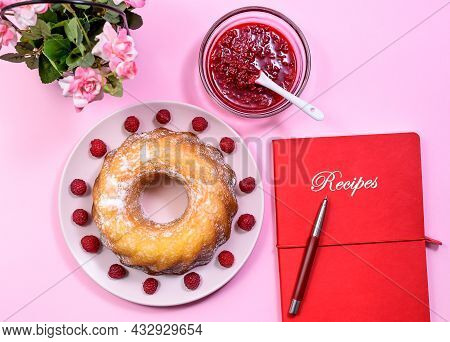 Homemade Kouglof Cake With Icing Sugar Dressing, Raspberries And Raspberry Filling, Along Red Book O
