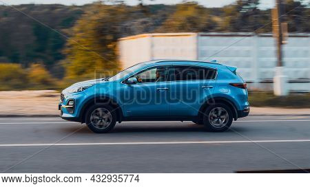 Side View Rolling Shot With Blue Kia Sportage In Motion. 4th Generation Ql Series Driving Along Coun