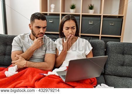 Young latin ill couple having medical teleconsultation using laptop at home.
