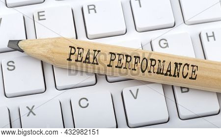 Text Peak Performance On Wooden Pencil On White Keyboard. Business