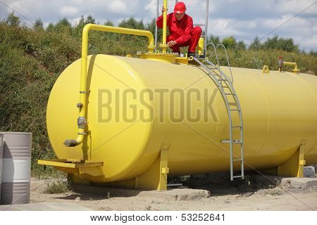 technician in red uniform working on large fuel tank 
