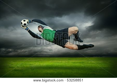 Football goalman with ball in action outdoors
