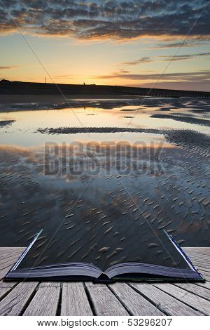 Creative Concept Pages Of Book Vibrant Sunrise Landscape Reflected In Low Tide Water On Beach