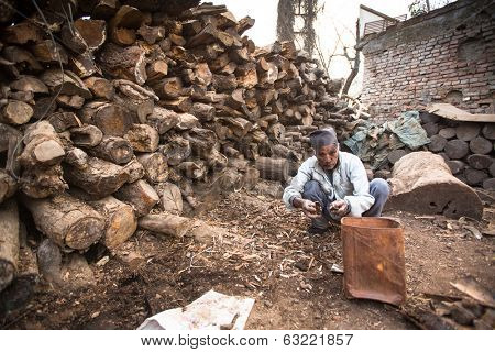 KATHMANDU, NEPAL - DEC 19, 2013: Unidentified a man sort wood for cremation rites in Bhasmeshvar Ghat at Pashupatinath temple in Kathmandu. 