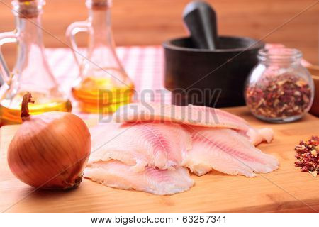Raw fish tilapia on cutting board and spices