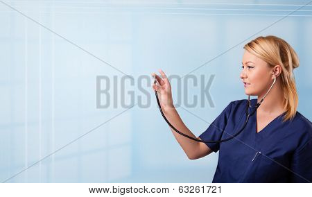 Pretty young nurse in hospital listening to empty copy space with sthetoscope