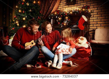 Happy family celebrating Christmas at home by the fireplace and the Christmas tree.