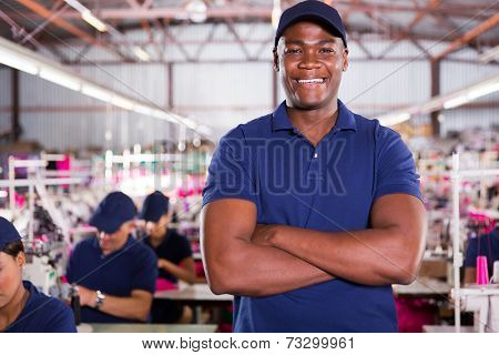 handsome african american factory supervisor with machinists on background