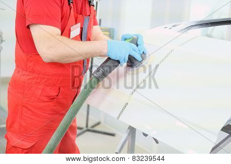 Painter polishes a car body component