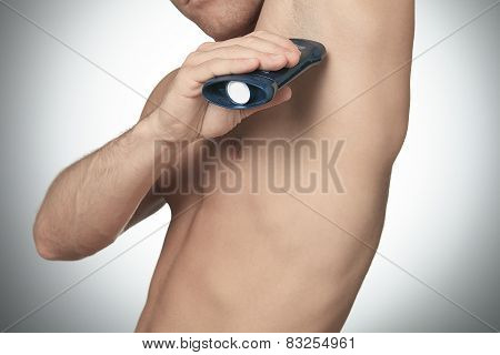 A Man uses deoderant on studio gray background