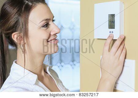 A woman set the thermostat at house.