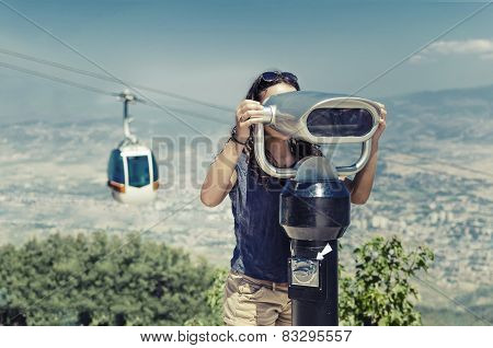 Girl looking through coin operated binoculars on a mountain peak