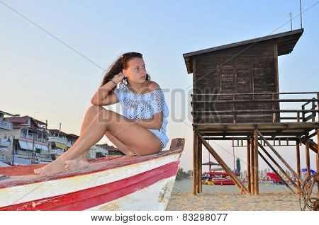 Beautiful girl sitting on a boat on the beach