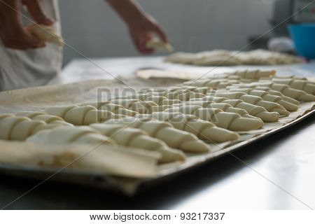 Baker Putting Unbaked Croissants Onto Tray