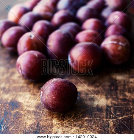 Fresh plums on a dark wooden table. Ripe Plums Texture over vintage wood background. Top view image.
