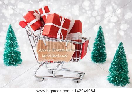 Trollye With Christmas Presents Or Gifts. Snowy Scenery With Snow And Trees. Sparkling Bokeh Effect. Label With German Text Am 6. Dezember Ist Nikolaus Means December 6th Is Nicholas Day