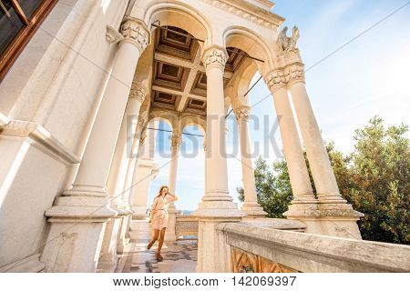 Happy woman running on the castle terrace near the sea. General plan with columns and arches