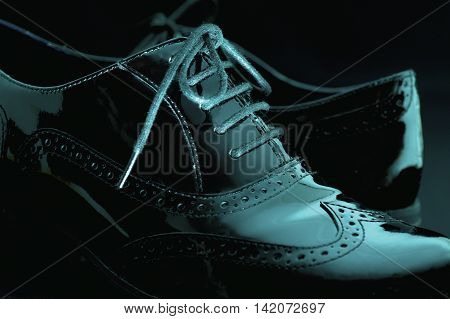 Footwear Concept. Horizontal Image. Pair of black female classic leather shoes on the black background. Selective focus. Blue colored.