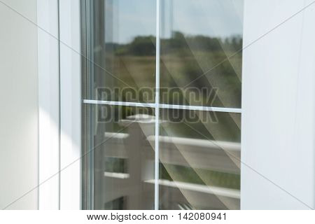 Plastic white window muntin bars with the reflection of the blue cloudy sky with green trees