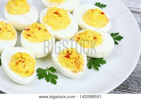 Deviled eggs filled with a delicious blend of yolks,  mayonnaise, mustard and spices decorated on top of egg with red paprika