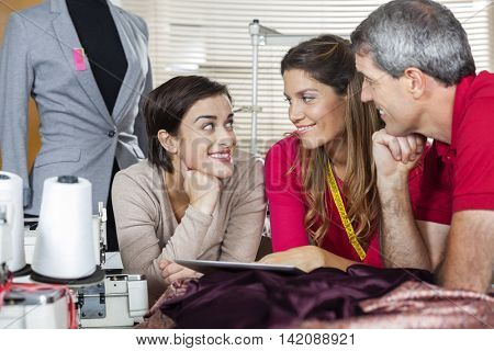 Happy Tailors Using Tablet Computer In Factory