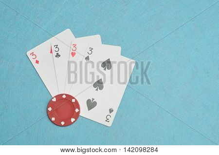 The different suits of a the number 3 card in a deck of cards displayed on a blue background with a poker chip