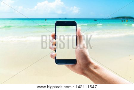 Hand using smartphone mobile in the vertical position, blur the background of the sea.