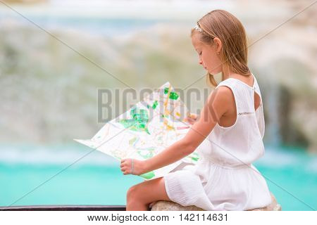Young beautiful girl near fountain Fontana di Trevi with city map