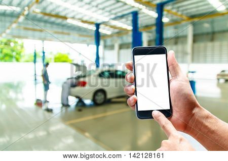 hand hold smartphone with car repair service center background blur