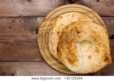 Traditional Uzbek bread on a plate on a wooden background